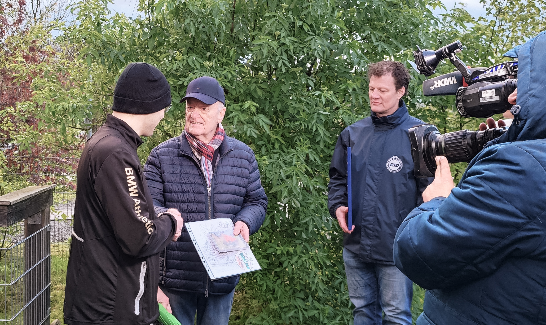 Reinhard Grüber, Ehrenvorsitzender des Verschönerungsvereins Waldbröl (Mi.), übergibt Antony Peter-Konrad (li.) die Weltrekord-Urkunde (Foto links).