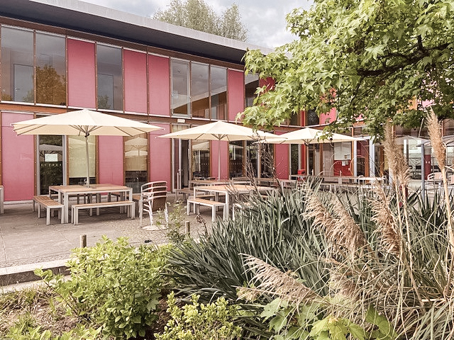 Eine Terrasse mit Tischen, Bänken und Sonnenschirmen