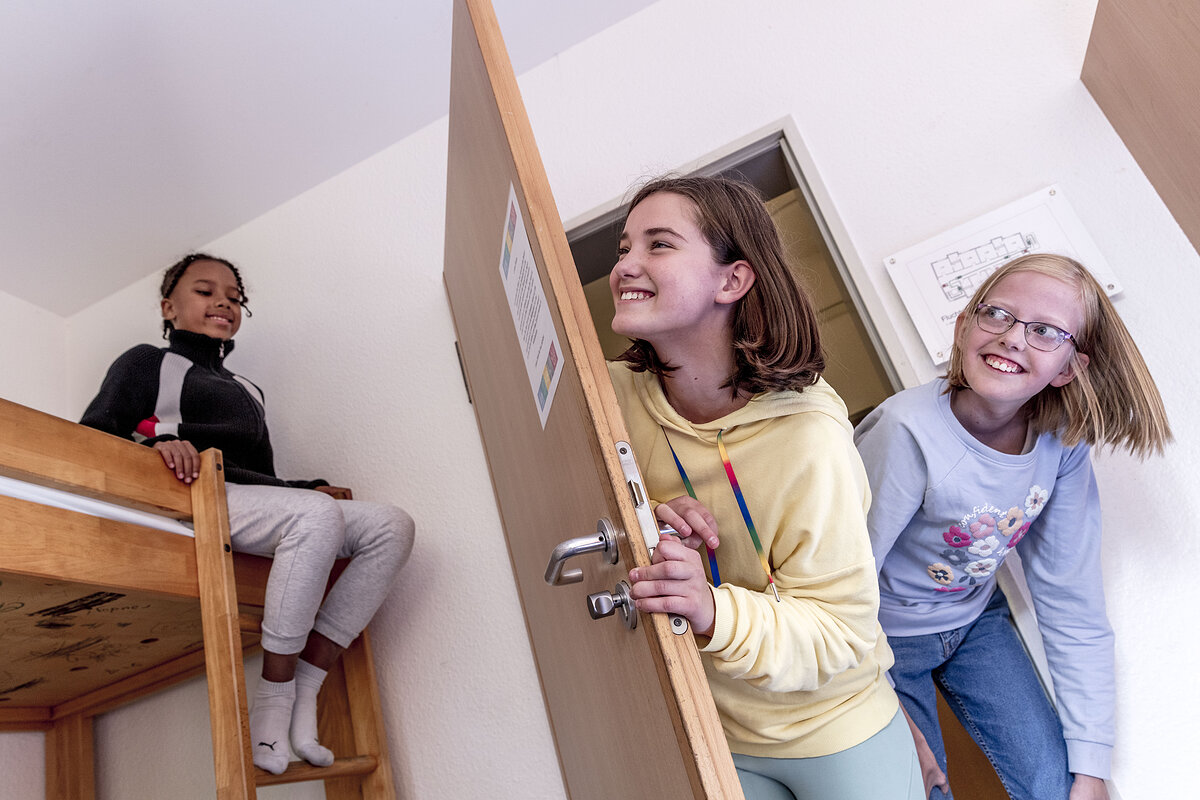 Zwei Mädchen kommen in ein Zimmer mit Stockbetten und lachen