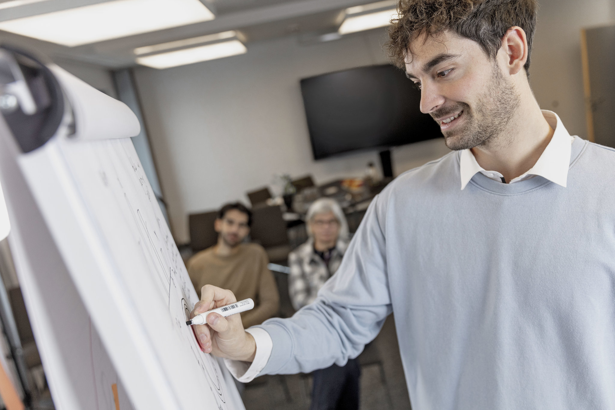 Ein Junger Mann schreibt auf einem Flipchart