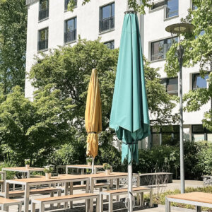 Terrasse mit Tischen, Bänken und Sonnenschirmen