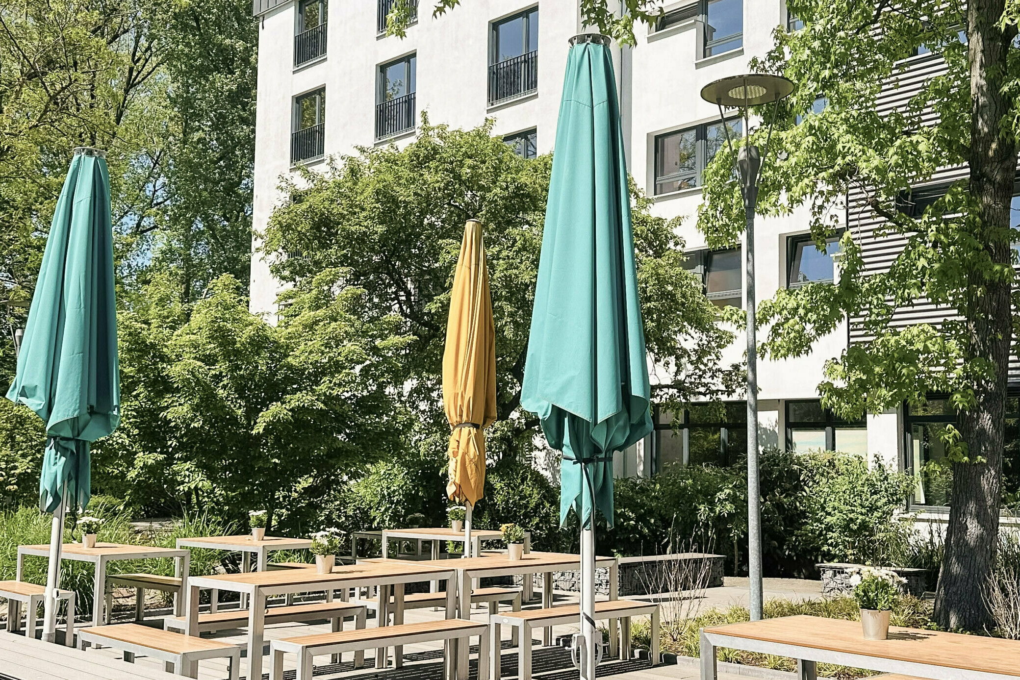 Terrasse mit Tischen, Bänken und Sonnenschirmen