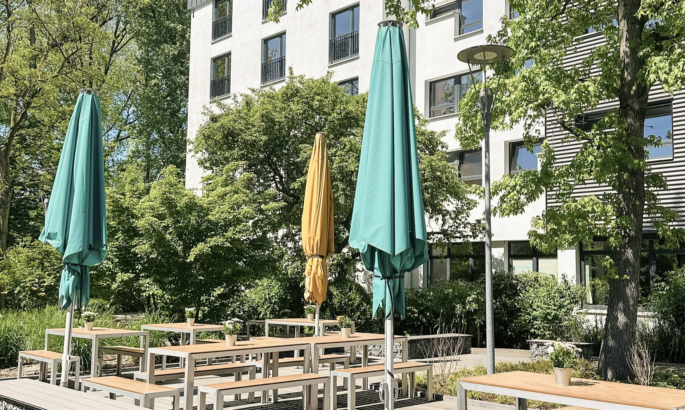Terrasse mit Tischen, Bänken und Sonnenschirmen