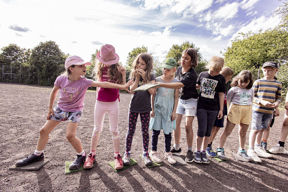 Kinder auf einem Sportplatz bei einer Teamaufgabe