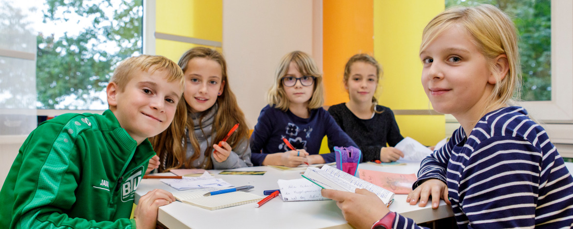 Vier Kinder sitzen gemeinsam an einem Tisch und lernen