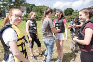 Mehrere Personen legen im Freien Schwimmwesten an.