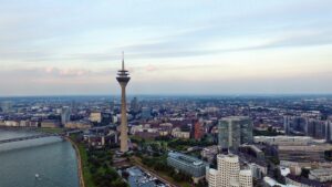 Luftaufnahme des Rheinturms und der Düsseldorfer Skyline am Flussufer bei Abenddämmerung