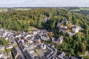 Luftaufnahme einer Stadt mit engen Gassen, alten Gebäuden und zwei Burgen auf einem Hügel.