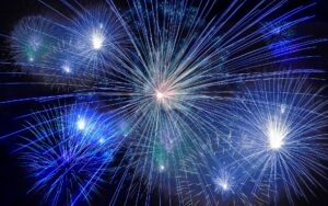 Mehrere blaue und weiße Feuerwerksexplosionen am nächtlichen Himmel