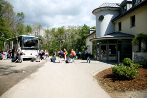 Ein Bus vor der Jugendherberge Wiehl. Kinder laufen mit Gepäck vom Bus zum Eingang der Jugendherberge.