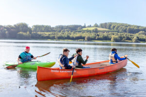 Kanu fahrende Kinder auf dem Baldeneysee unter strahlend blauem Himmel
