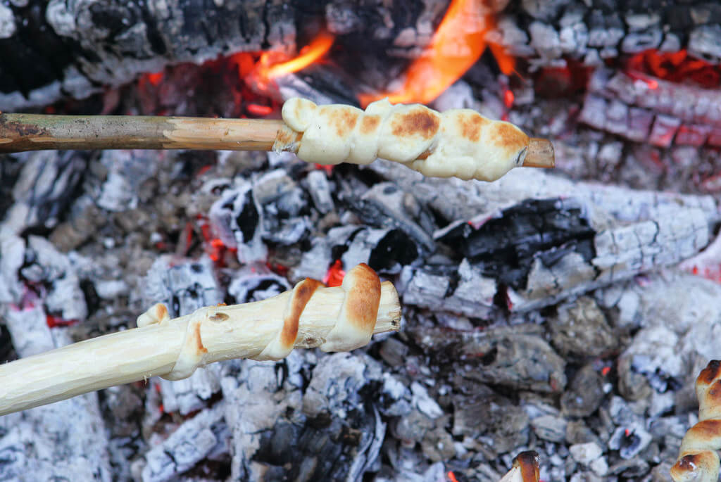 Zwei Stockbrote werden an einem Lagerfeuer gebacken