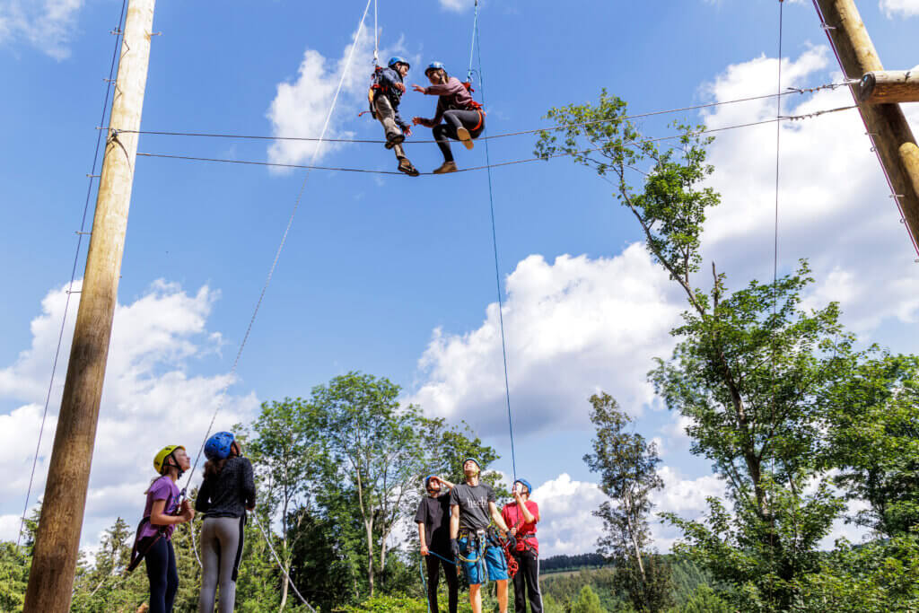 Zwei Personen klettern gemeinsam in einem Hochseilgarten