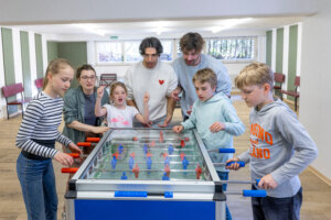 Zwei Männer und mehrere Kinder beim gemeinsamen Kicker-spielen